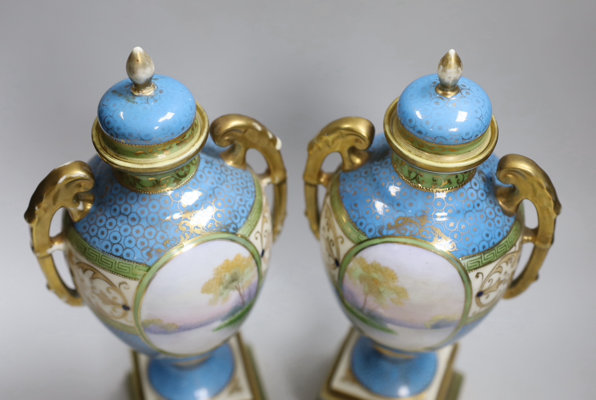 A pair of Japanese Noritake vases and covers, each hand painted with a river landscape, 29cm high